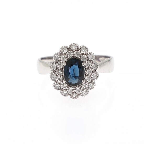 A ring set with a sapphire weighing app. 0.76 ct. encircled by numerous diamonds weighing a total of app. 0.42 ct., mounted in 18k white gold. Size 56.