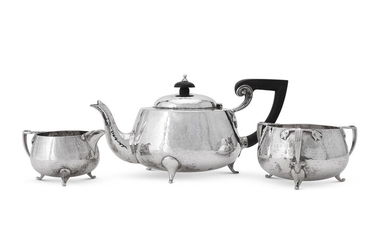AN ARTS AND CRAFTS HAMMERED SILVER THREE PIECE TEA SERVICE, BARKER BROTHERS
