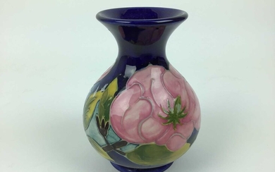 Moorcroft pottery vase decorated in the Magnolia pattern on blue ground, impressed marks to base, 13cm high