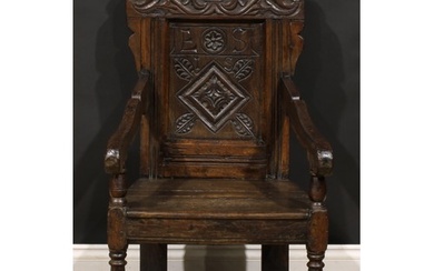A 17th century oak wainscot armchair, shaped cresting carved...