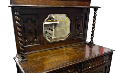 A 1920s oak mirror back sideboard with an arrangement of...