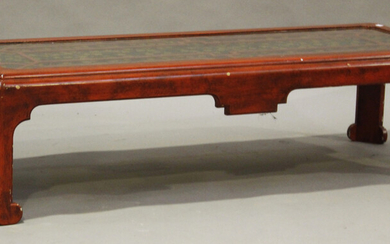 A 20th century red lacquered rectangular coffee table, the top inset with glass covering a gilt leaf