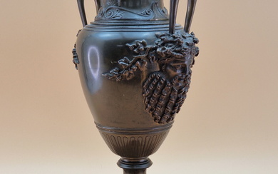 A BRONZE BALUSTER VASE, THE TWO HANDLES WITH BEARDED MASK TERMINALS, THE FOOT RESTING ON BLACK