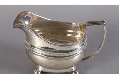 A GEORGE III SILVER CREAM JUG of oblong form with gadroon ri...