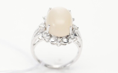 A MOONSTONE AND DIAMOND DRESS RING IN 18CT WHITE GOLD, CENTRALLY SET WITH AN OVAL CABOCHON CUT MOONSTONE OF 9.58CTS, IN A BORDER OF...