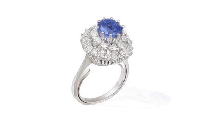 A SAPPHIRE AND DIAMOND CLUSTER RING The cushion-shaped sapphire weighing...