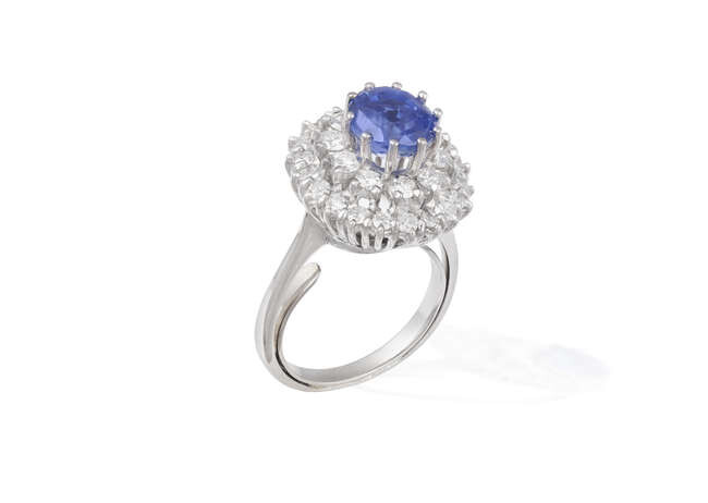 A SAPPHIRE AND DIAMOND CLUSTER RING The cushion-shaped...