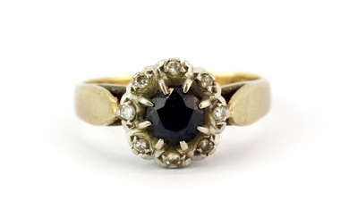 A hallmarked 9ct yellow gold cluster ring set with a round cut sapphire surrounded by diamonds, (M.5).