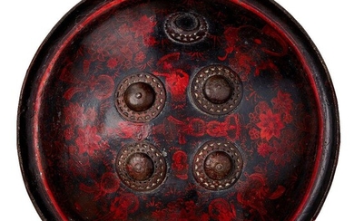 A lacquered rhino hide shield with figurative decoration, Rajasthan, India, late 18th century, of circular form, the monochrome figural decoration arranged around four applied bronze bosses depicting various deities interspersed with exuberant...