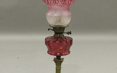 A late 19th/early 20th century brass and cranberry glass table oil lamp, fitted with a frosted pink