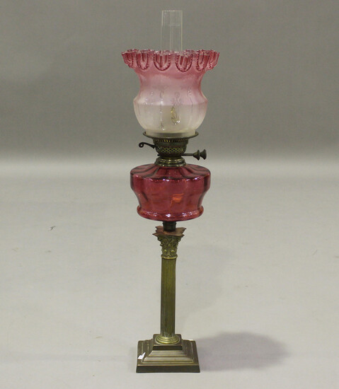 A late 19th/early 20th century brass and cranberry glass table oil lamp, fitted with a frosted pink