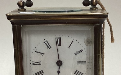 A small brass carriage clock with white enamelled dial.