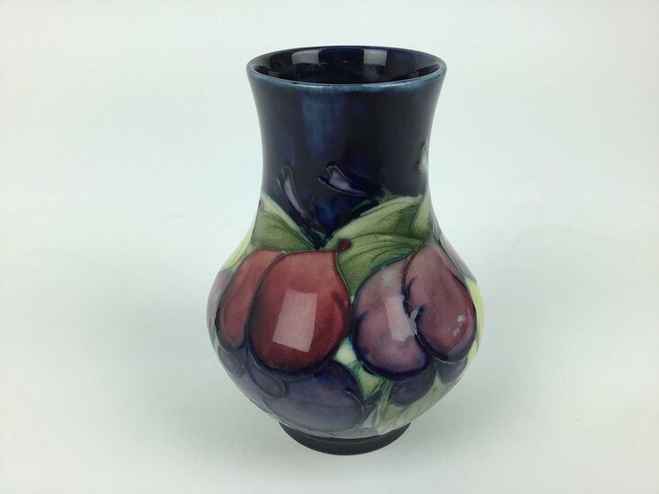 Moorcroft pottery vase decorated in the Wisteria pattern on blue ground, impressed marks and blue painted signature to base, 12.5cm high