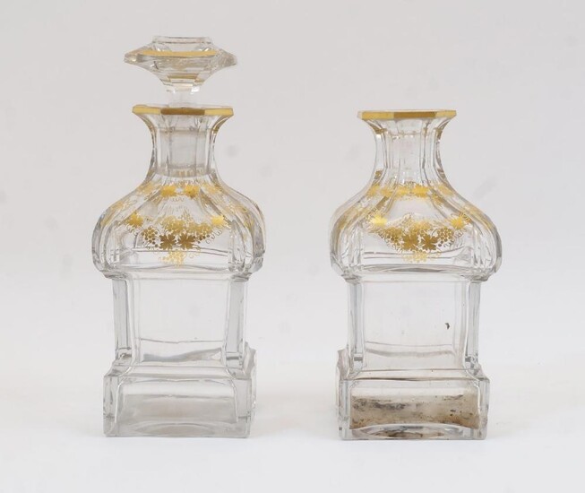 Two glass decanters, 19th century, each with octagonal necks leading to rectangular bodies with canted edges, the necks with gilt grape and vine decoration, one with similarly decorated stopper, 20cm high overall (2)