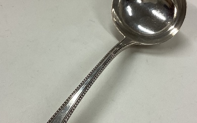 A George III silver bottom marked sauce ladle with crested and beaded decoration.