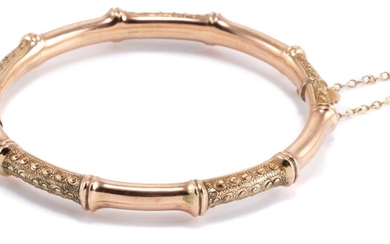 A VINTAGE 9CT GOLD BAMBOO STYLE BANGLE; hinged with concealed clasp and safety chain, internal dim. 58 x 53mm, wt. 11.23g.