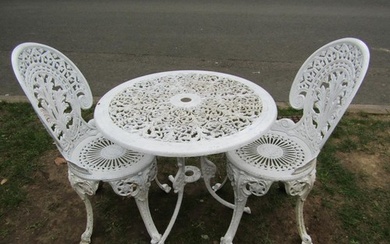 A cream painted cast aluminium garden table of circular form...