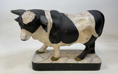 A large painted model of a cow on wooden base...