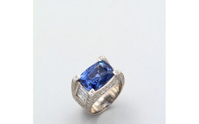 A large platinum ring adorned with a cushion-cut natural sapphire set with four diamond claws, the sides of the setting paved with brilliants and baguette-cut diamonds.x000D_
