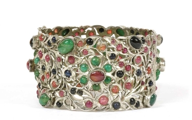 A silver hinged emerald, ruby and sapphire set bangle