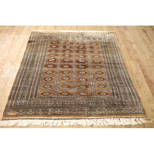 AN ORIENTAL WOOL RUG the light brown and gold ground with ce...