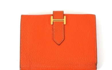 NOT SOLD. Hermès: A "Mini Bearn" wallet made of orange leather with gold toned hardware,...