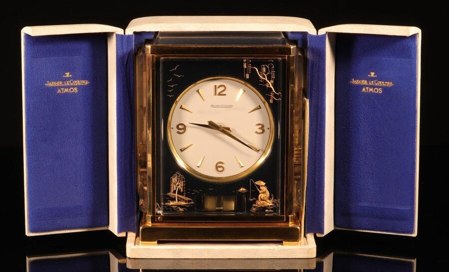 Horloge - JAEGER-LECOULTRE. Pendule "Atmos" en métal doré et plexiglas à décor en inclusions de motifs état neuf coffret et document d'origine