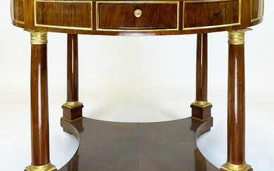 Tavolo circolare lastronato in mogano con quattro cassetti nella fascia con profili dorati e montanti a colonna a tutto tondo…
