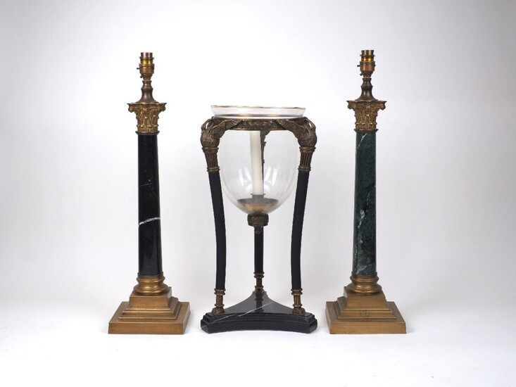 Two modern gilt metal mounted marble column table lamps, one with a black marble shaft, the other green, 45cm high excluding fitment; together with a modern Regency style brass and glass candle holder, of triform with swan supports, on a marble...