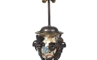 A Neo-Classical urn shaped lamp, late 19th century, the ceramic painted body decorated with leaf and vine motifs, with spelter mounts in the form of scrolling acanthus terminating in faun masks and classicising female busts, on a black plinth base...