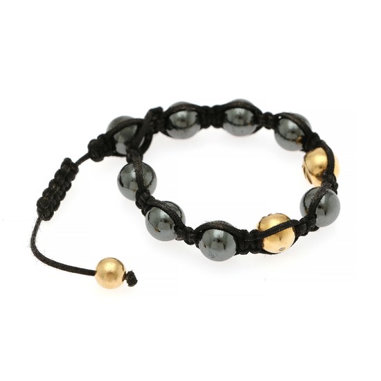 A bracelet of braided string set with eight hematite beads and two 18k gold beads each set with a brilliant-cut diamond. L. app. 17.5 cm.