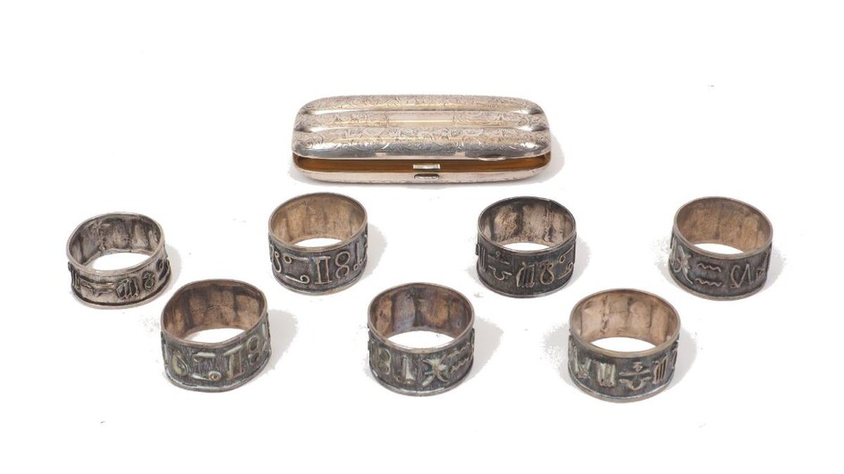 A cased set of six astrology-inspired napkin rings, apparently unmarked, assumed silver, each decorated with astrological symbols, together with a seventh matching napkin ring and a Victorian silver cigar case, Birmingham, c.1898, Rose & Brough...