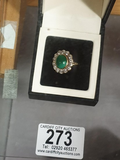 A ladies 18k gold dress ring with green stone surrounded by ...