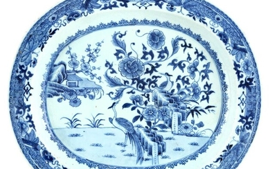A large Chinese blue and white meat dish, 18th century, of oval shape raised on a flat base, painted to the centre with cranes among flowers and rocks, 39.5cm diameter 十八世紀 青花繪花鳥圖紋大盤