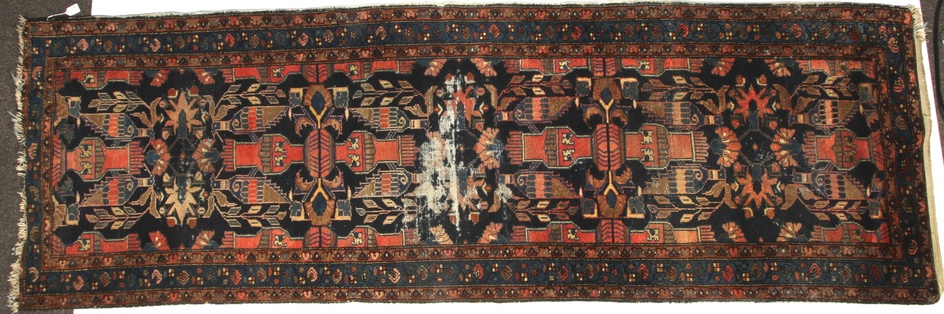 A late 19th/early 20th century wool runner, probably South Caucasian. Woven with stylised vases and birds in red, pink and yellow, on a dark blue ground, within geometric and foliate borders, 97.5cm x 297cm
