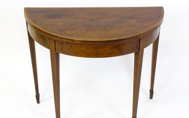 A late Georgian mahogany demi lune card table with a crossbanded top above four tapering legs