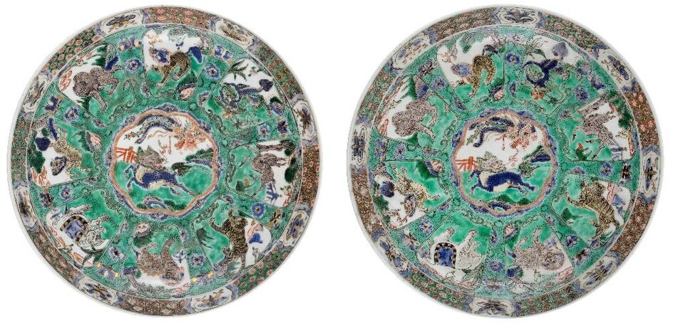 A pair of Chinese famille verte dishes, Kangxi period, painted to the centre with qilin and phoenix at play, surrounded by panels each enclosing a mythical beast below a floral border embellished with butterfly cartouches, the exterior painted with...