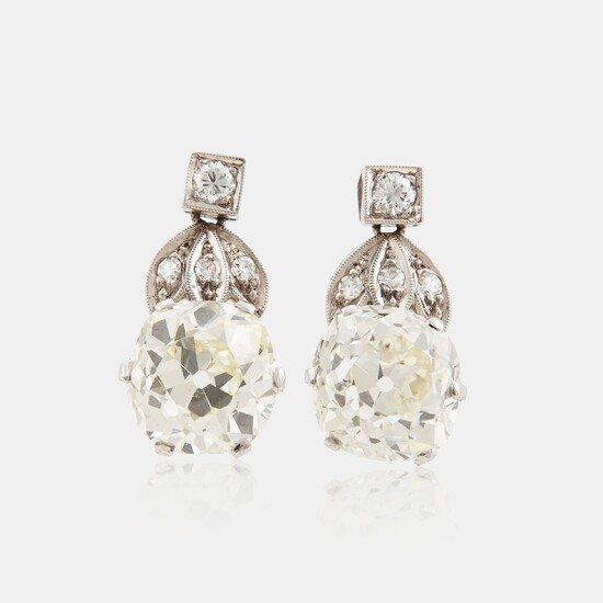 A pair of platinum earrings set with cushion formed old-cut diamonds with a total weight of ca 6.00 cts quality ca L/M v