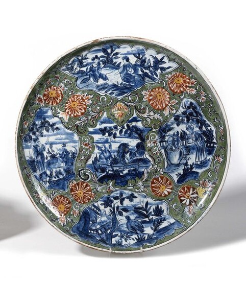 Delft (kind of) Round Chinese dcb earthenware dish in landscapes on a green flowery background. Beginning of the 20th century. D. 41,5 cm.