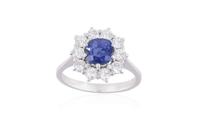 Description A SAPPHIRE AND DIAMOND CLUSTER RING The cushion-shaped...
