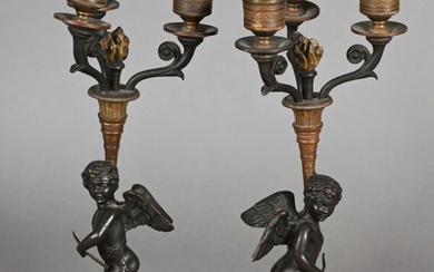 Paire de candélabres en bronze patiné et doré figurant deux cupidons tenant une torche supportant...