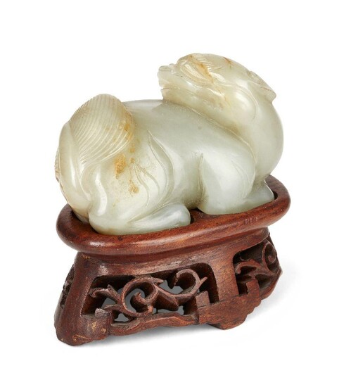 Property of a Gentleman (lots 36-85) A Chinese celadon green and russet jade lion dog, 17th century, in recumbent pose with head turned over its right shoulder, with finely detailed brows and broad tail, 6.5cm long, later fitted wood stand...