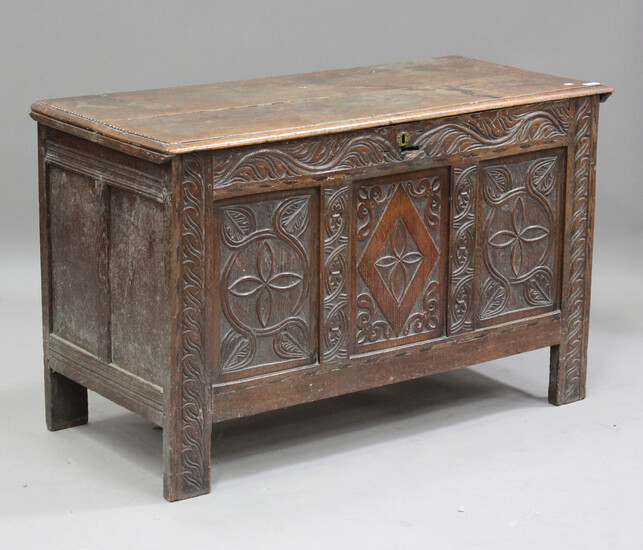 A late 17th/early 18th century oak coffer, the hinged lid above a carved triple panel front, on stil