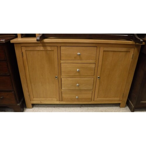 A modern light oak sideboard with four central drawers flank...