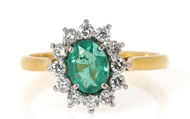 An emerald and diamond ring set with an oval-cut emerald encircled by...