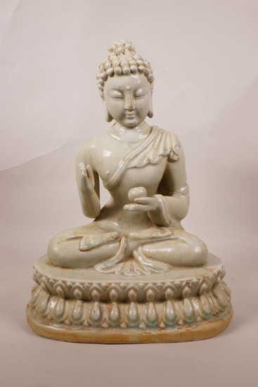 A Chinese celadon glazed pottery figure of Buddha seated on ...