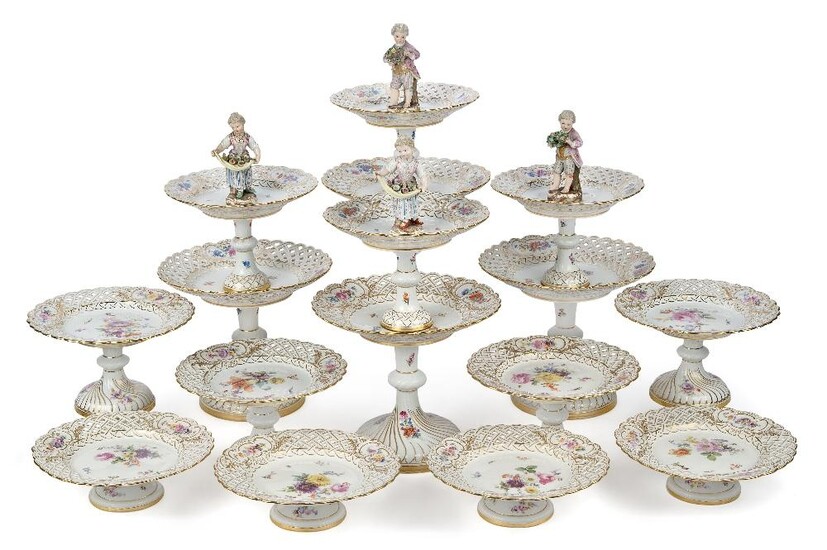 A Meissen composite part dessert service, late 19th century, hand-painted with blossoming flowers and butterflies and with alternating reticulated lattice and cartouche borders, comprising: four two-tiered cake stands, two surmounted by a figural...