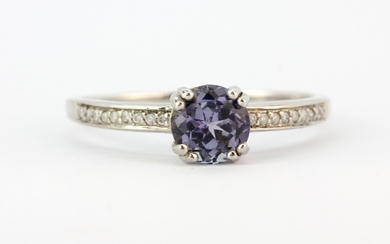 A hallmarked 9ct white gold ring set with a round cut tanzanite and diamond set shoulders, (U).