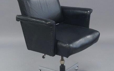 A mid century black leather swivel desk chair, reclining, raised on chrome supports and castors