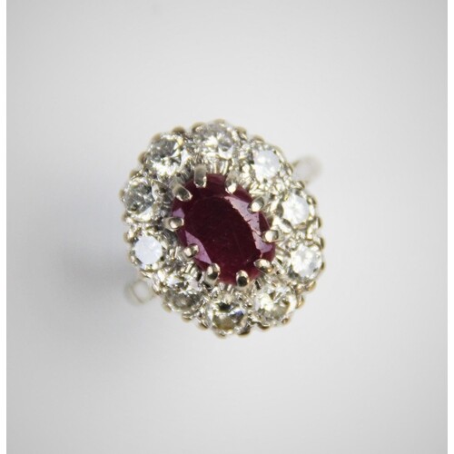 A ruby and diamond cluster ring, comprising a central oval m...